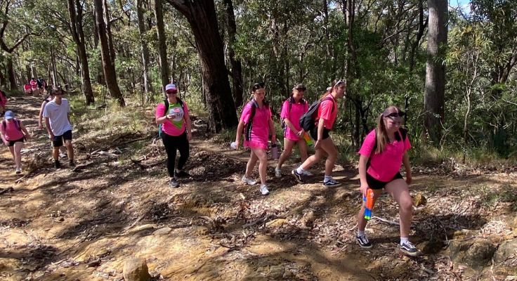 Students dressed in pink and walking up a mountain