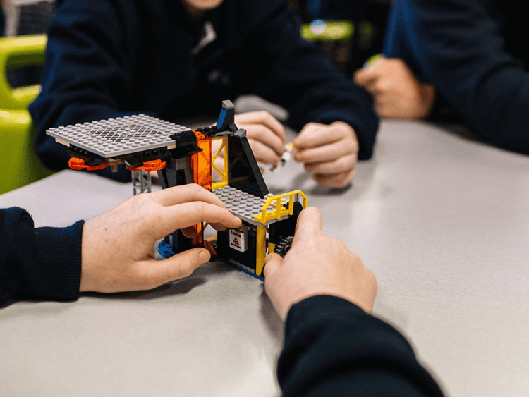 Two sets of student hands building lego