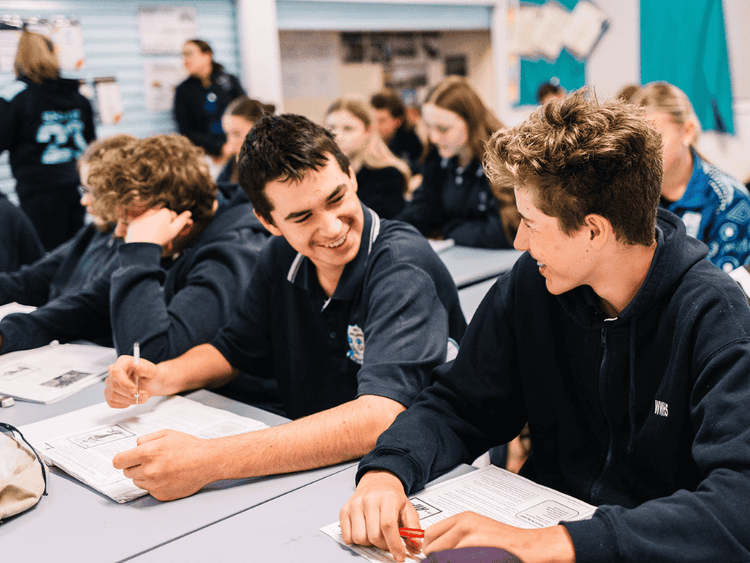 An image of two male students in class smiling