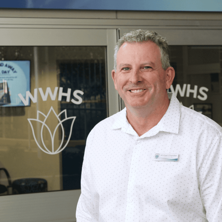 An image of the school principal standing at the front of the school and smiling