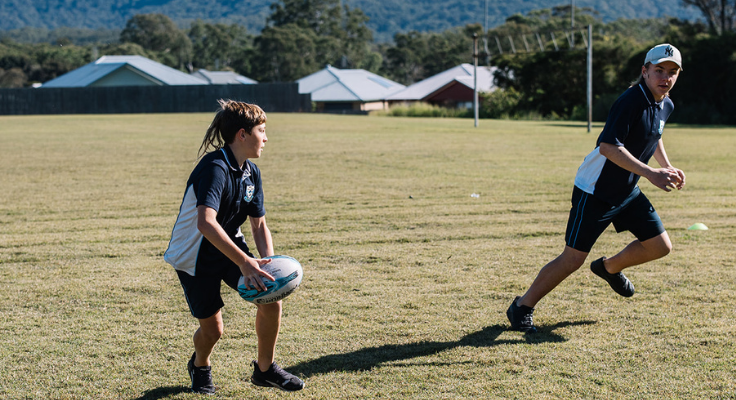 Two boys playing rugby league on an oval