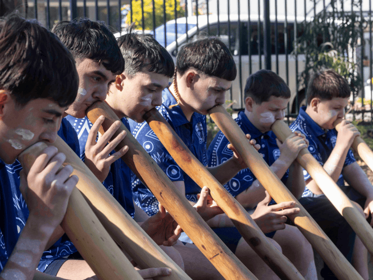 An image of a group of Aboriginal boys playing yidaki instruments